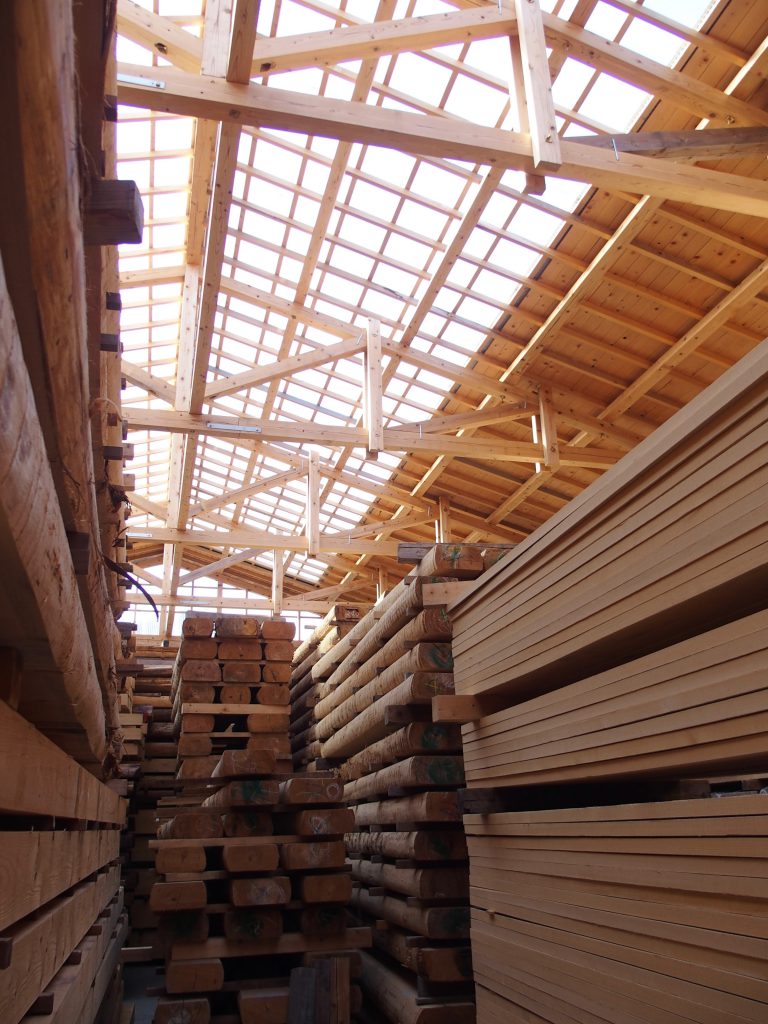 写真：木で組まれた工場の内部。たくさんも木材が積み上げられている。